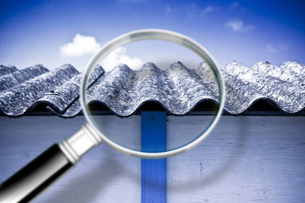 Magnifying glass analyzing dangerous asbestos roof panels, highlighting the importance of safe asbestos testing and removal services.